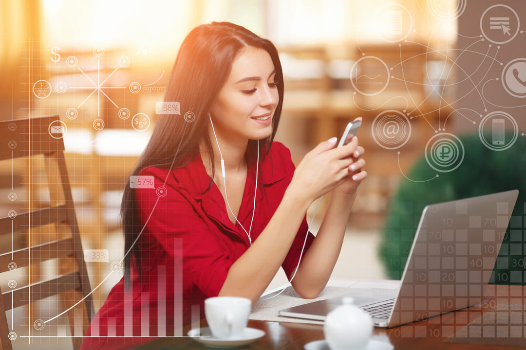 Uma jovem mulher sentada em um ambiente iluminado e aconchegante, usando uma camisa vermelha e fones de ouvido brancos, está sorrindo enquanto interage com seu smartphone. Em frente a ela, há um laptop e uma xícara branca sobre a mesa. A imagem apresenta elementos gráficos sobrepostos, como gráficos de barras, porcentagens e ícones relacionados à tecnologia e comunicação, criando um efeito futurista e digital.